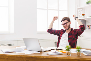 Young happy businessman in office with computer