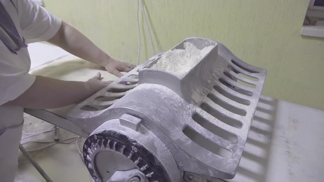 Baker preparing flaky at dough roller machine in bakery HD video. Sheeter operator making layered dough for pastry production