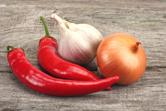 spices onion, garlic and chili pepper on old wood background