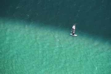 Fototapeta premium Man windsurfing in two colored sea aerial photo.