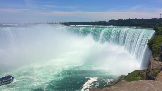 Boot kommt ins Bild gefahren auf Wasser bei Niagara Wasserfällen in Kanada