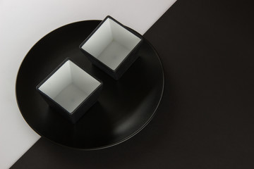 A number of flat plates and cups on black and white background