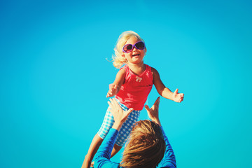 Father and little daughter play at sky