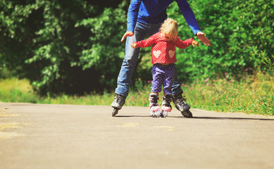 father teaching little daugther to roller skate