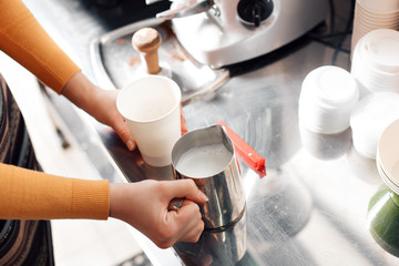barista steaming milk churns for cappuccino, coffee machine, selective focus