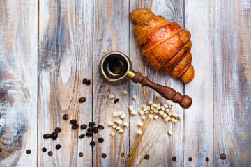 Morning coffee and fresh croissant on wooden table