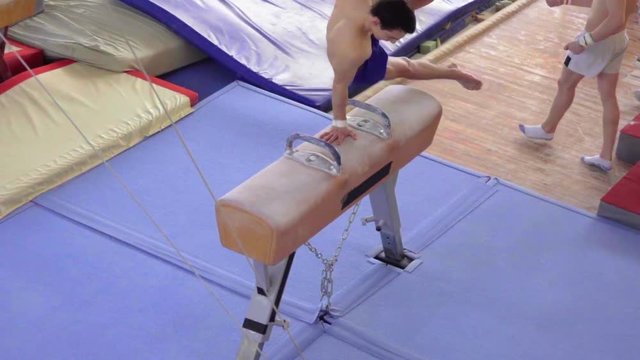 Gymnast doing exercises on pommel horse HD slow-motion video. Olympics athlete training gymnastics: circles scissors flairs trick performing