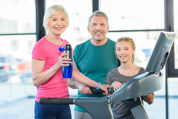 Fototapeta na wymiar old sport couple and girl training on treadmill in fitness class
