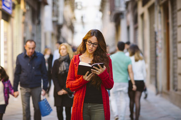 Portrait of a beautiful woman reading a book on the middle of the street.