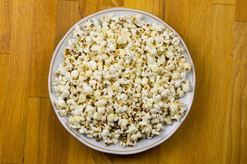 Ceramic plate with white air corn on a wooden table background bar counter light snack at the party