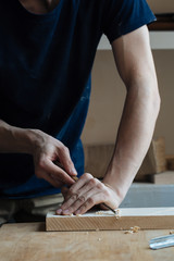 Wood carving, the master's hands work with a wooden surface, a professional does wood crafts