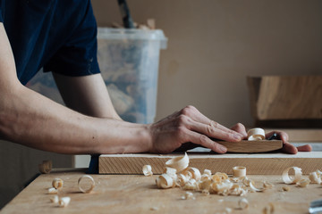 Wood carving, the master's hands work with a wooden surface, a professional does wood crafts