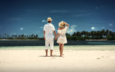 A guy and a girl in white clothes on the shore of the island. Maldives. White sand. Guraidhoo.