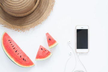 Fresh watermelon with smartphone and hat, Summer concept flat lay on white background