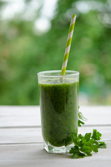 Green smoothie with  parsley  as healthy summer drink on wooden table