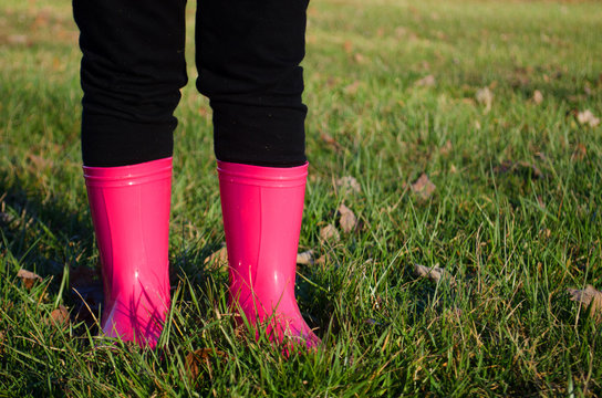 Child wearing pink rain boots on the grass