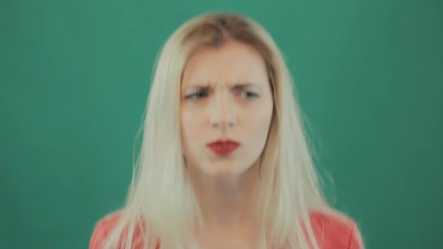 Portrait of Angry Pretty Blonde Woman on Green Background. Emotional Young Girl with Long Hair and Sensual Red Lips in Studio.