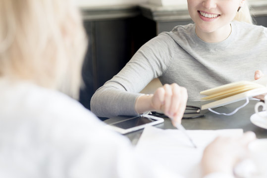 Close-up of two women with notebook, document and cell phone