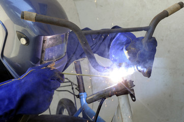 A worker welding steel to repair old bicycle