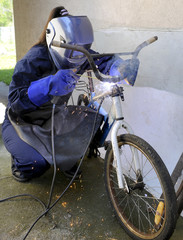 A worker welding steel to repair old bicycle