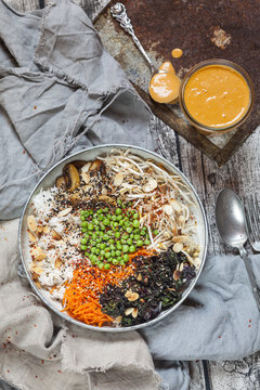 Buddha bowl of kale, carrot, mung bean sprouts, rice, peas, button mushrooms, and roasted almonds
