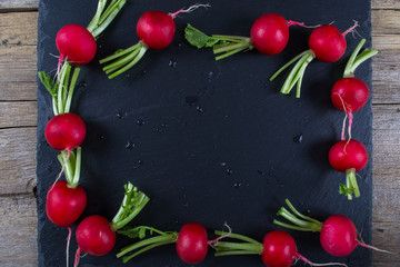 Spring fresh radishes frame  on the black slate board, top view
