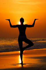Kobieta ćwicząca jogę na plaży przy zachodzie słońca - obrazy, fototapety, plakaty