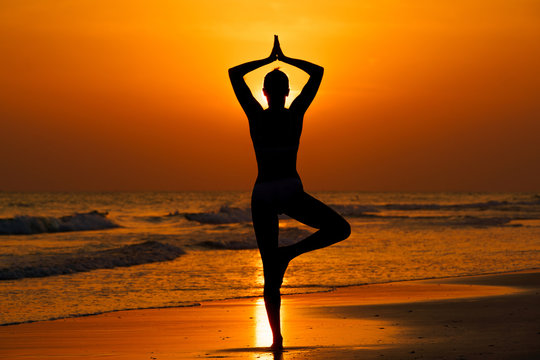 Kobieta ćwicząca jogę na plaży przy zachodzie słońca © piotrszczepanek