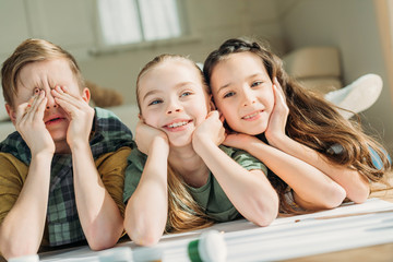 cute kids painting on paper with while lying on floor at home