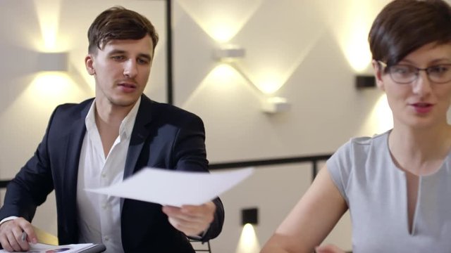 Slow motion footage of young entrepreneur passing document to colleague at meeting