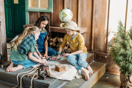 cute kids playing treasure hunt with map on porch