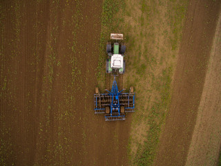 aerial view of a tractor at work - tractor plough cultivating beautiful fields  - agricultural machinery