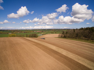Fototapeta na wymiar Aerial view of beautiful agricultural fields in spring with a tractor at work - tractor plough cultivating fields
