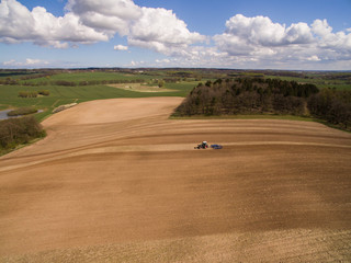 Aerial view of beautiful agricultural fields in spring with a tractor at work - tractor plough cultivating fields