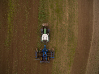 aerial view of a tractor at work - tractor plough cultivating beautiful fields  - agricultural machinery