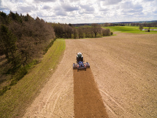 aerial view of a tractor at work - tractor plough cultivating beautiful fields  - agricultural machinery