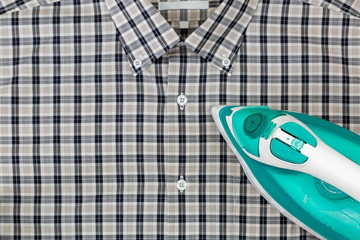 Steam iron in green with aluminum soleplate, water in tank, ironing clothes, checked black white shirt