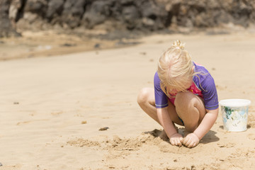 Little Girl Playing with Sand in the Beach