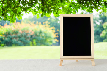 Blank chalkboard standing on sack tablecloth over blur tree background, space for text, mock up, product display montage