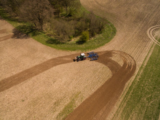 aerial view of a tractor at work - tractor plough cultivating beautiful fields  - agricultural machinery