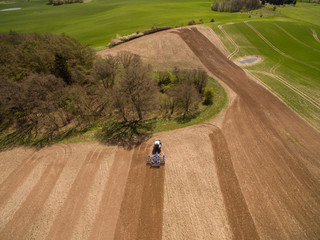 Aerial view of beautiful agricultural fields with a tractor at work - tractor cultivating a field