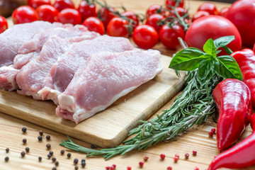 Raw pork on cutting board and vegetables