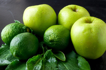 Ingredients for smoothie. Green fruits on black wooden background. Apple, lime, spinach. Detox. Healthy food. Top view. Copy space.