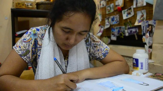 Thai designer women drawing and design pattern fashion on paper for make mood board on table at home office on April 19, 2017 in Nonthaburi, Thailand