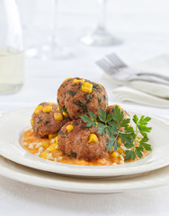 Meatballs with corn and parsley served on a white plate