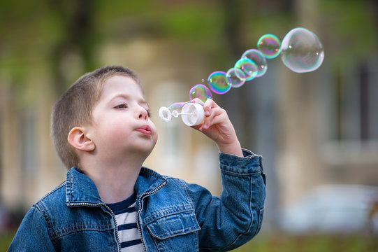 little boy blowing soap bubbles in a park