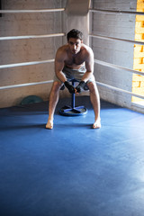 Fototapeta na wymiar Young boxer sitting in the corner of boxing ring