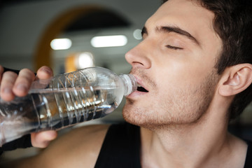 Man sportsman drinking water after training