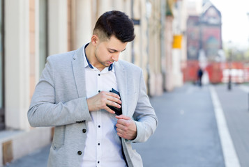 young businessman take in his wallet on his jacket pocket on street