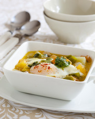 Fish stew with coriander leaves an a poached egg
